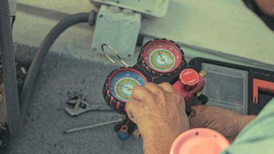 A technician connecting air-conditioning gauges under the bonnet of a car.